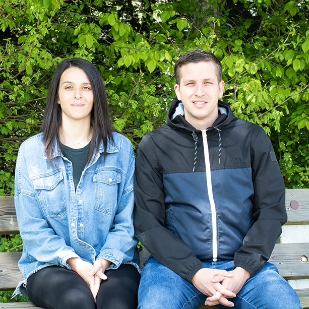 Laura and Orlando sitting on a bench in their Cornol village